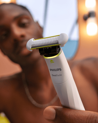 Kobieta trzymająca pionowo Philips OneBlade Intimate, prezentująca trymer z ostrzami ze stali nierdzewnej pochodzącej z recyklingu