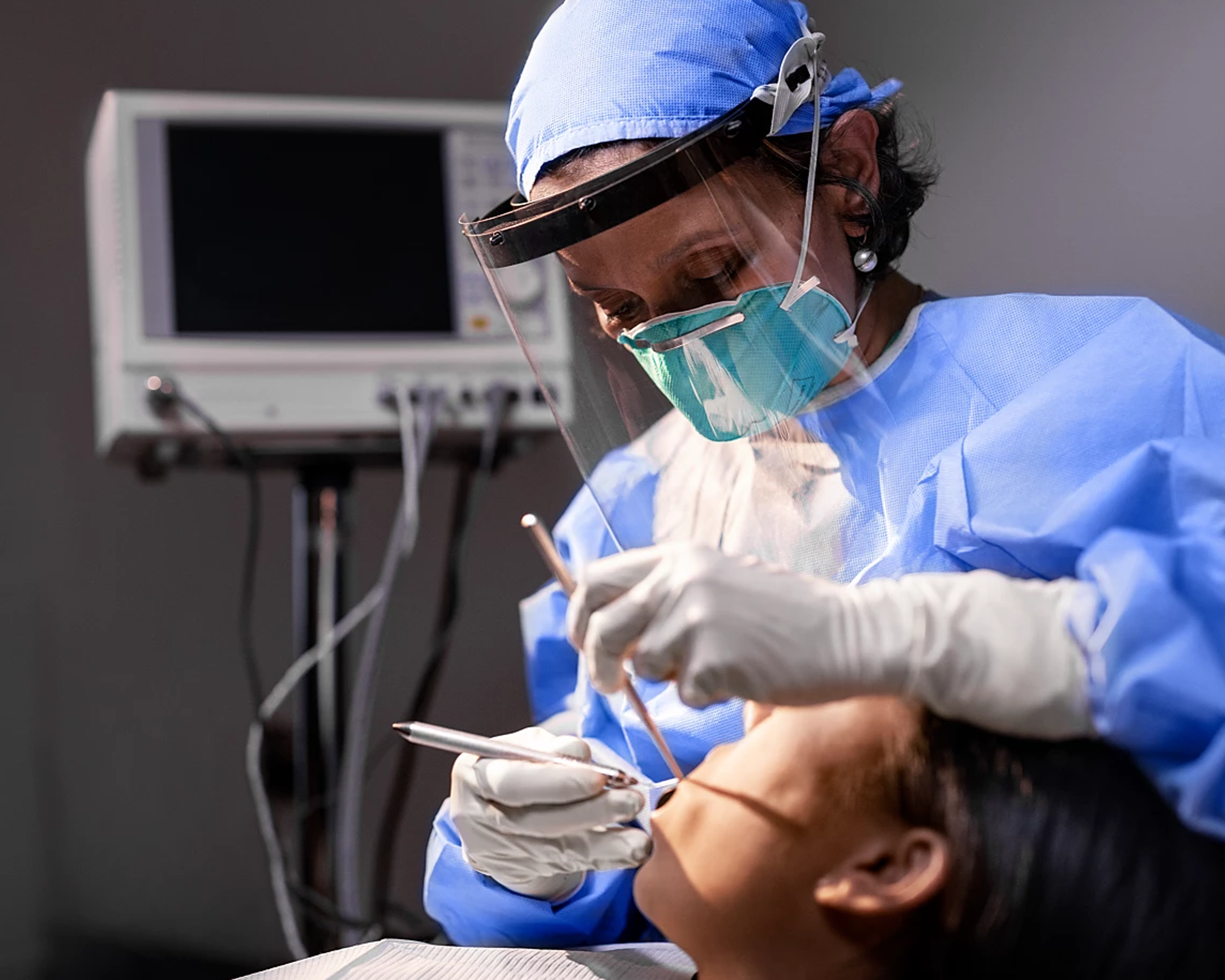 A dental professional working on a patient in a dental chair.