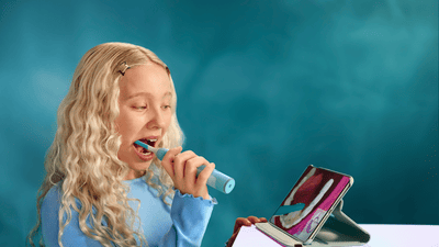 A child brushes her teeth with a Philips Sonicare for Kids Smart toothbrush, while using the Sonicare for Kids app.