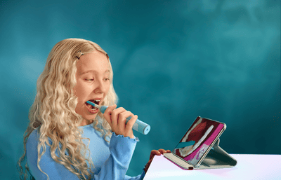 A child brushes her teeth with a Philips Sonicare for Kids Smart toothbrush, while using the Sonicare for Kids app.