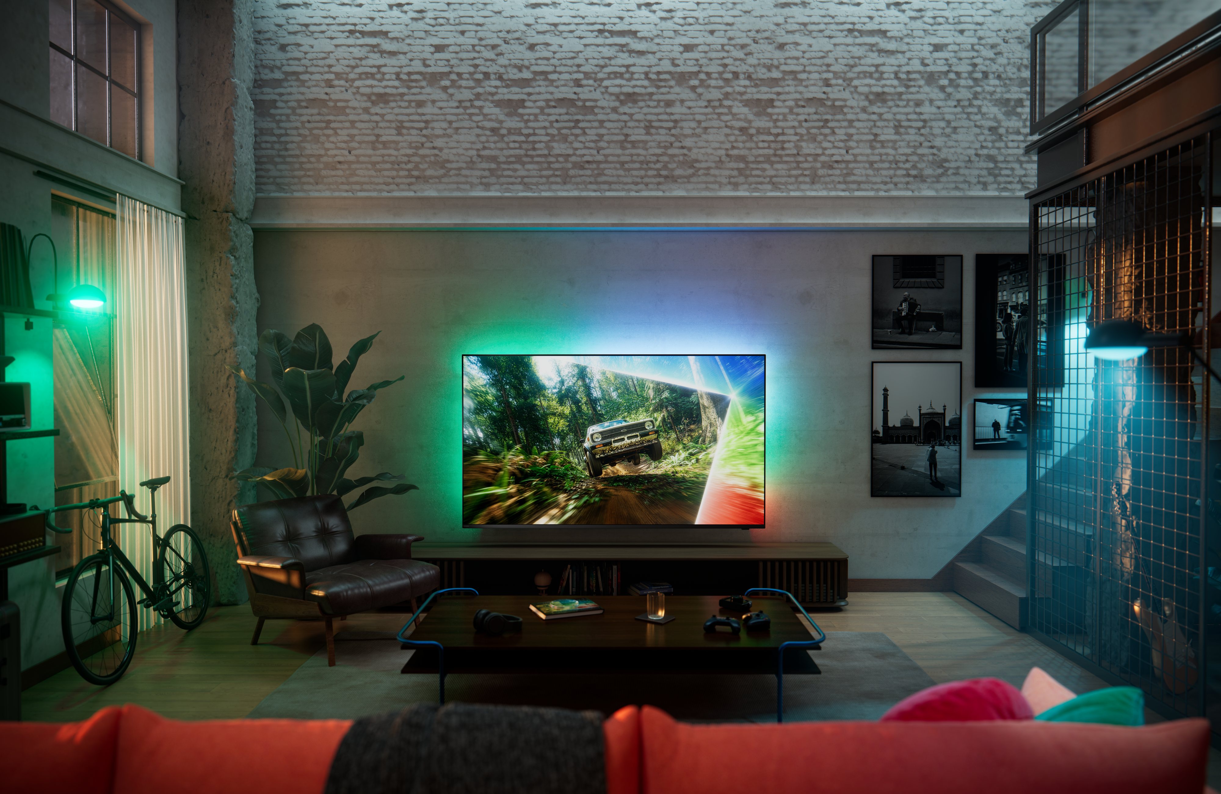 Philips Ambilight TV in a modern loft-style living room, displaying an off-road driving scene with immersive multicolored ambient lighting extending onto the wall behind the screen.