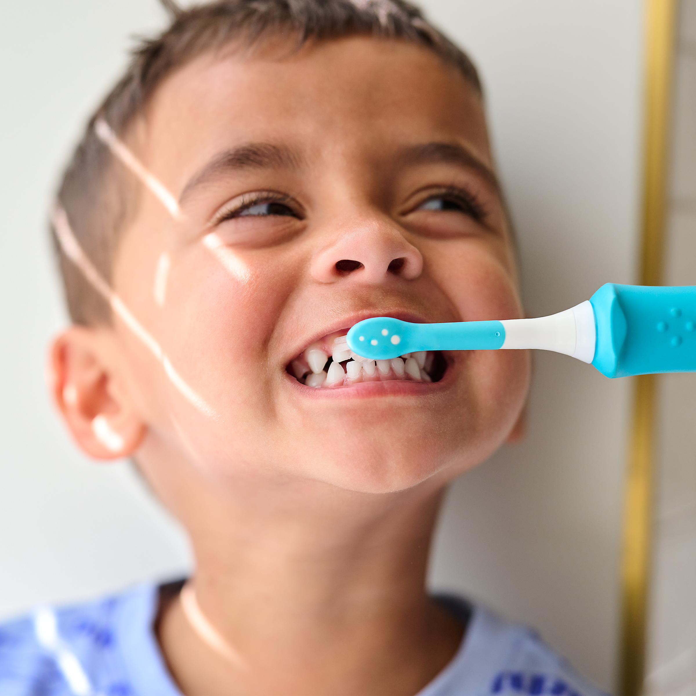 Child showing off smile while holding a Sonicare For Kids power toothbrush.