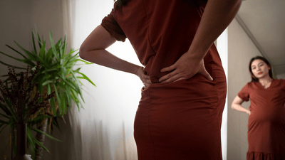 Silueta tehotnej ženy v okne pri východe slnka