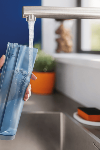 Ръка, държаща син воден резервоар