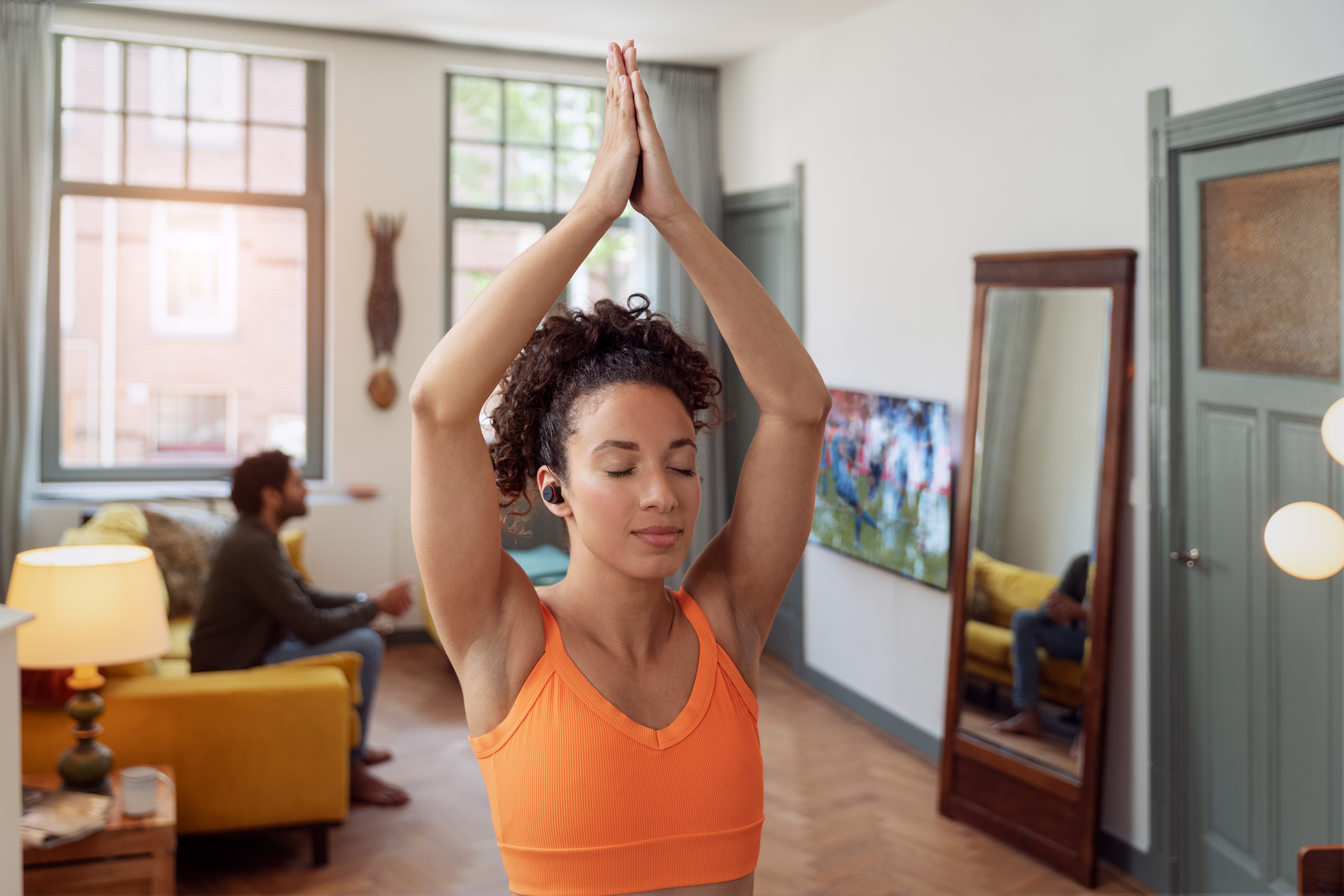 Žena cvičí jogu v interiéri so slúchadlami Philips s potlačením hluku.