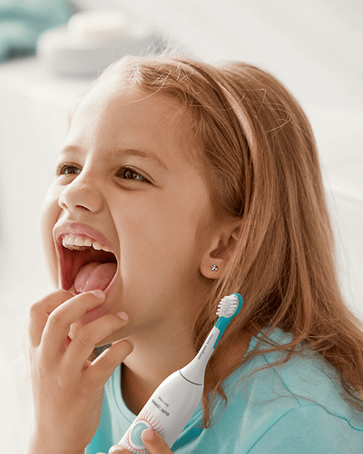 Laps naeratab, käes elektriline hambahari