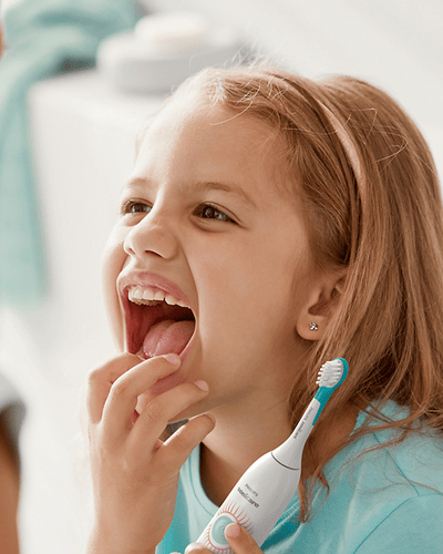Child smiling with an electric toothbrush in her hand