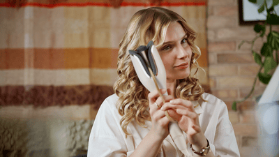 femeie cu par blond isi onduleaza parul cu ondulator automat