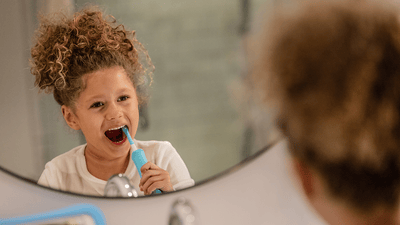 Copil care se spală pe dinți cu periuța de dinți electrică pentru copii