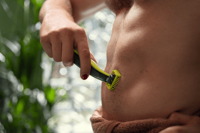 A man uses the Philips OneBlade 360 to shave his abdominal region.