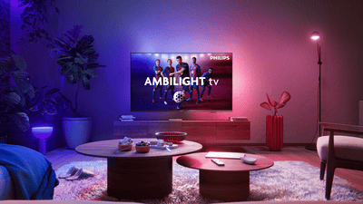 Philips Ambilight TV-n megjelenő FC Barcelona játékosok, amelyek színes háttérvilágítással világítanak meg egy modern nappalit.