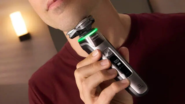 A close-up of a man shaving his chin with a Philips i9000 Prestige electric shaver.