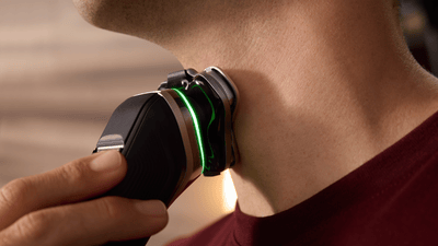 A close-up shot of a man shaving his neck using a Philips i9000 Prestige electric shaver.