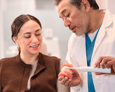 A dentist showing a patient how to brush with Sonicare.