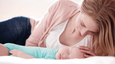 אמא מחבקת תינוק על מיטה נעימה