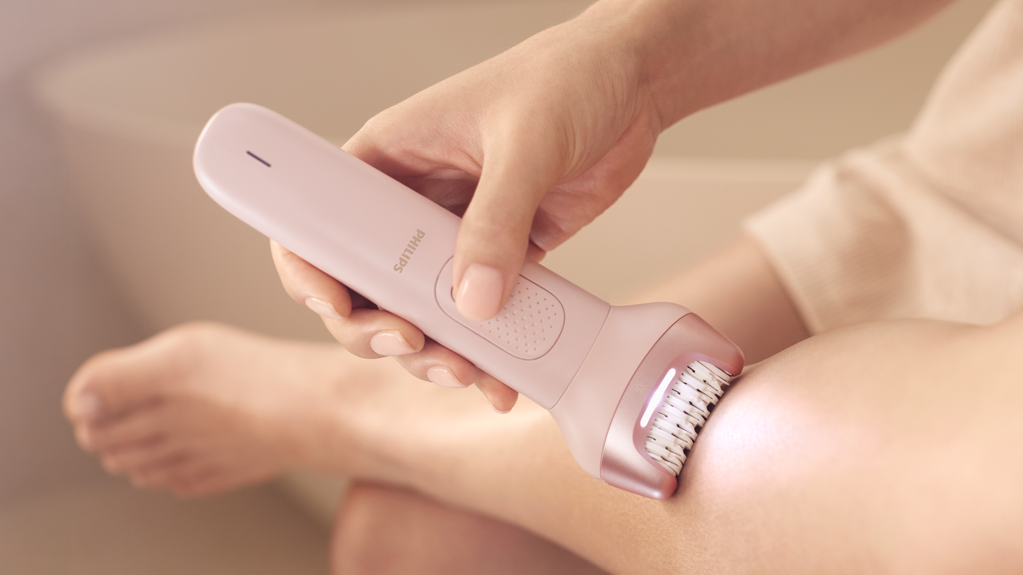 Woman using Philips epilator on legs for smooth results at home