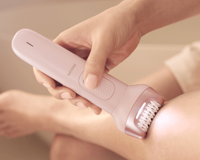 امرأة تستخدم جهاز إزالة الشعر من Philips على ساقيها للحصول على نتائج ناعمة في المنزل