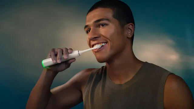 A young man brushes his teeth using a Philips Next-Generation DiamondClean electric toothbrush.