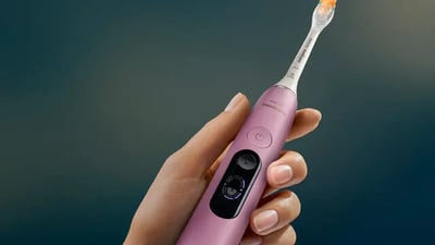 A close-up shot of a person holding a Philips Next-Generation DiamondClean electric toothbrush.