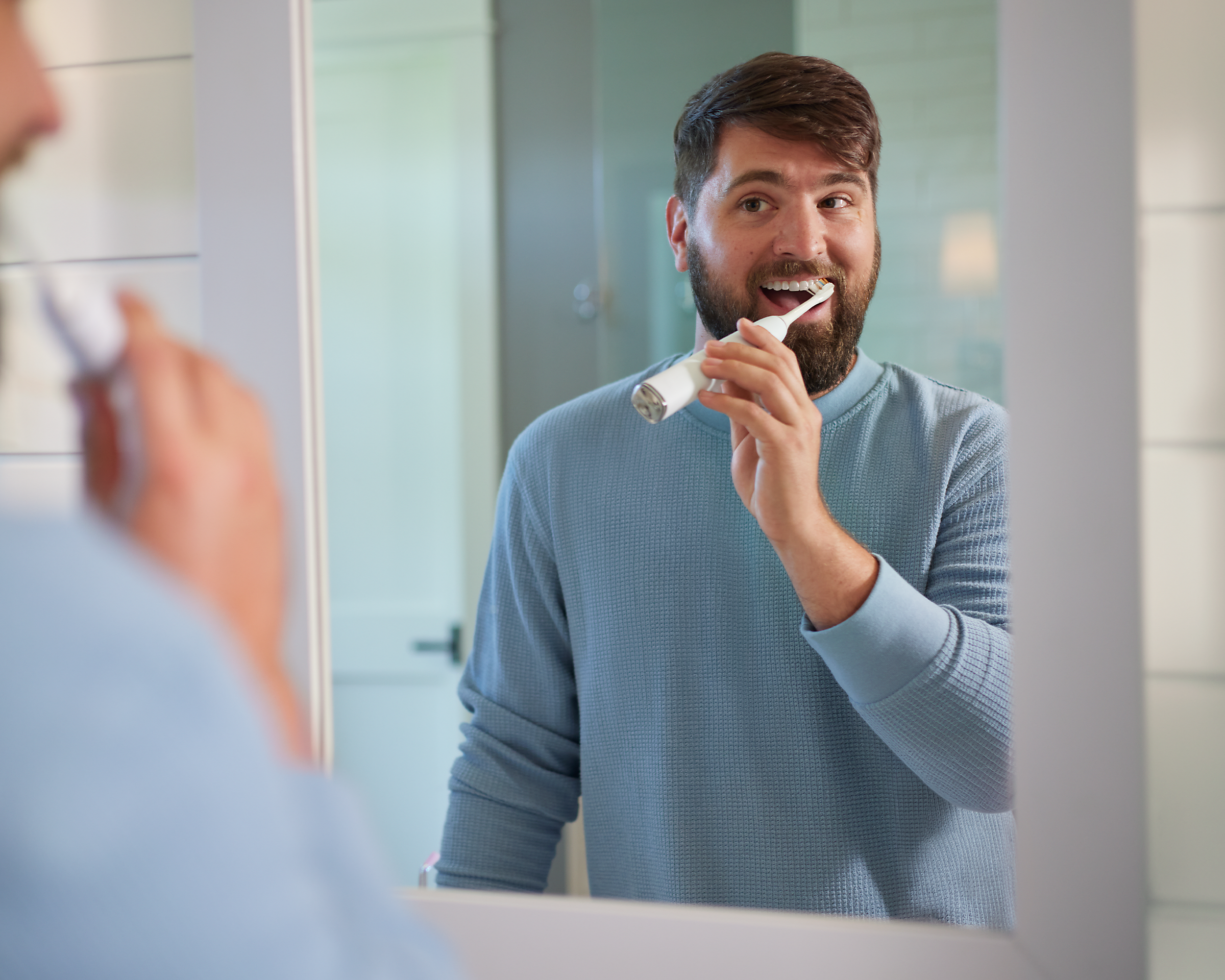 A man in the mirror brushing teeth