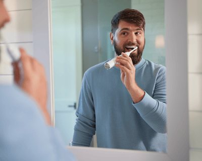 A man in the mirror brushing teeth