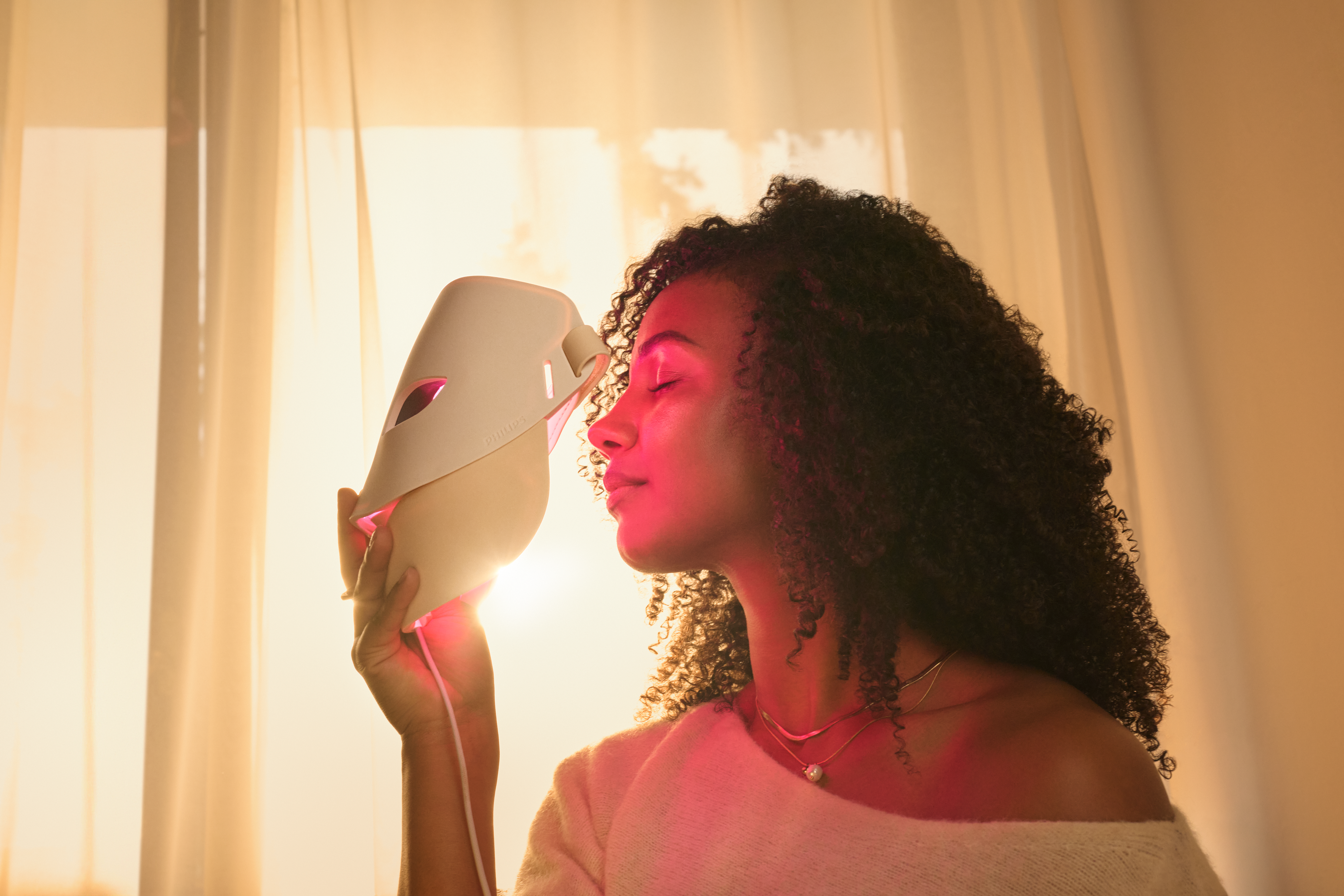 Person using Philips LED Face Mask in Daily Glow mode with red light therapy