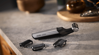 Produkt-Nahaufnahme eines schwarz-grauen Philips Bodygroom mit Körperkamm, der auf einer grauen Marmorplatte liegt.