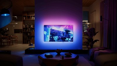 Philips Ambilight TV mounted in a modern living room, displaying a vibrant fantasy landscape while blue and purple ambient lighting extends beyond the screen onto the wall.