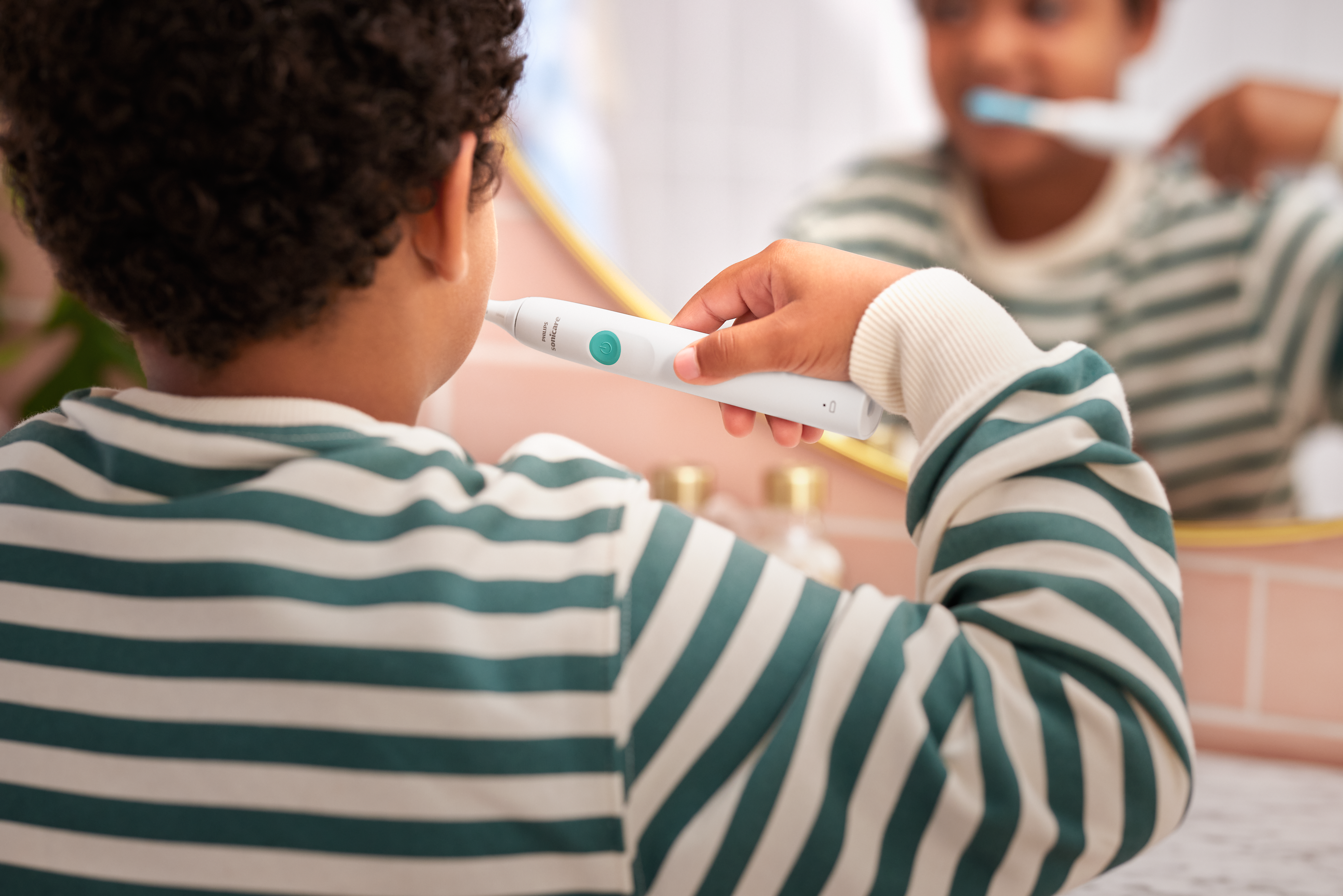 Un bambino si lava i denti davanti allo specchio.