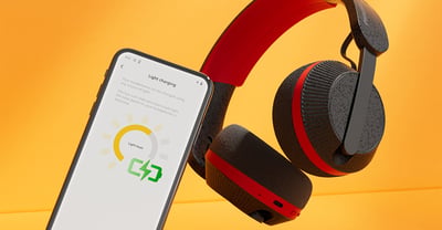 Philips A6219-koptelefoon naast een smartphone waarop het oplaadschermpje te zien is, tegen een feloranje achtergrond