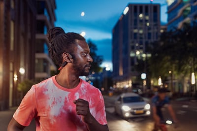 Atleet gebruikt bone-conduction-hoofdtelefoons op een drukke straat.
