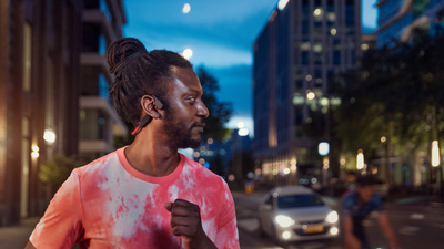 Športovec používajúci slúchadlá na kostné vedenie na rušnej ulici