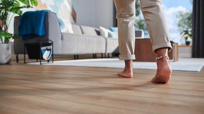 Bose stopy idące po ciepłej drewnianej podłodze