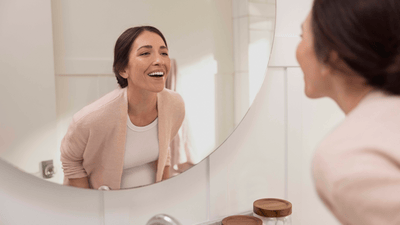 Žena si prohlíží zuby v zrcadle