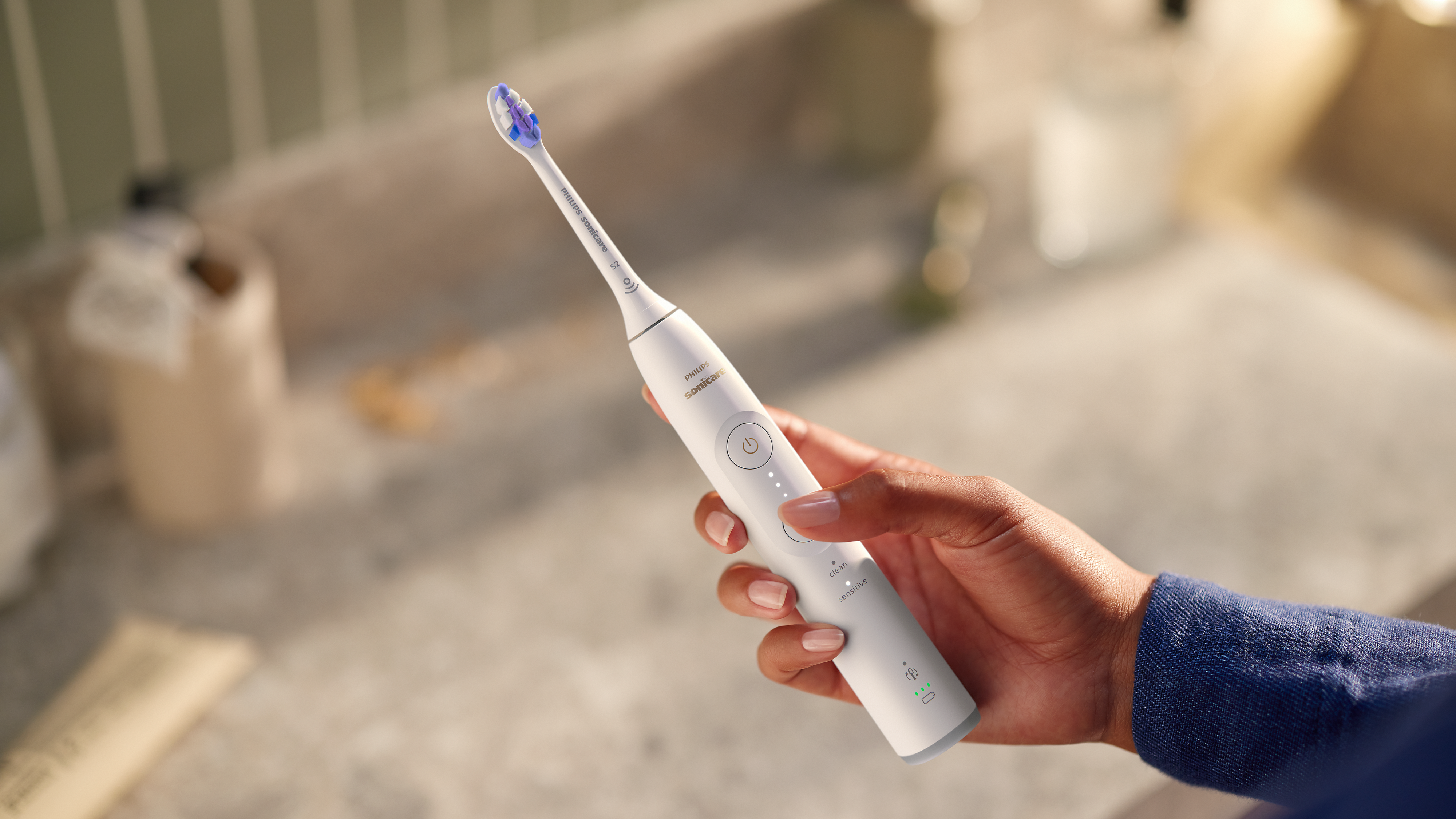 Una persona sostiene un cepillo de dientes eléctrico Philips blanco.