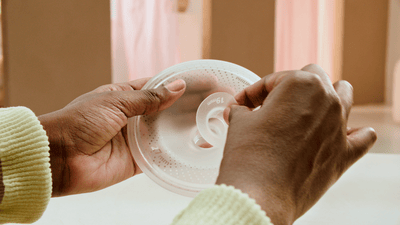 Un primo piano di una donna che pulisce e rimonta il suo tiralatte indossabile Philips Avent.