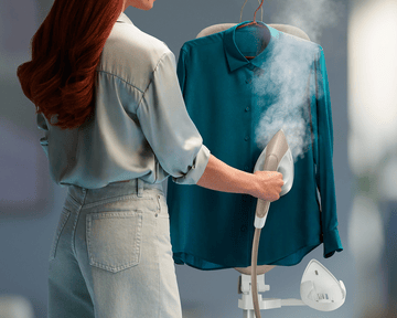 žena žehliaca košeľu parou