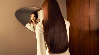 Păr lung și drept, șaten, reflectat într-o oglindă rotundă de perete.