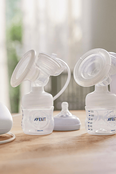 Mom talking to the phone while wearing breast pumps