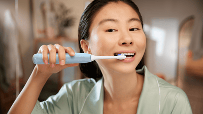 Joven sonriendo mientras se cepilla los dientes