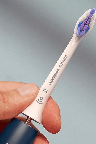 Hand die een Philips Sonicare Sensitive-opzetborstel vasthoudt
