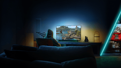 Person spielt Assassin’s Creed auf einem Philips Ambilight TV in einem stimmungsvoll beleuchteten Wohnzimmer.