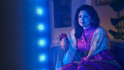 Žena gleda Philips Ambilight TV, plavo ambijentalno svjetlo odražava se pokraj zaslona.