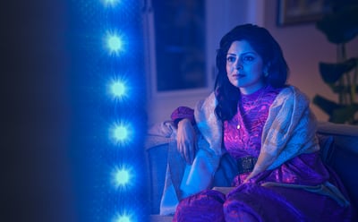 Frau schaut einen Philips Ambilight Fernseher, blaues Ambient-Licht reflektiert neben dem Bildschirm.