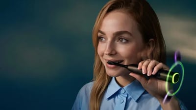 A young woman brushes her teeth using a Philips Next-Generation DiamondClean electric toothbrush.