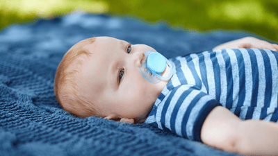 Detailní záběr dítěte, které leží na zádech a dudlá růžový dudlík