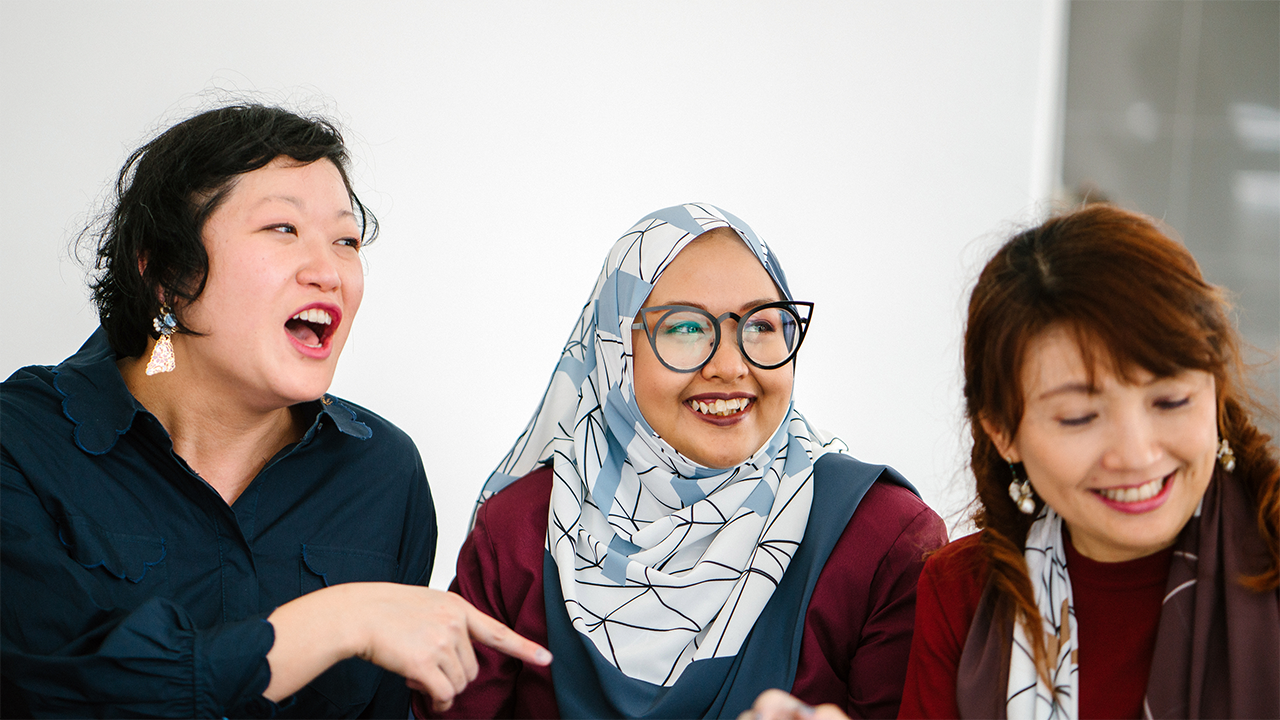 Three women of older adult age photographed smiling together in a social or wellness setting. The group dynamic conveys connection and peer support, representing the mental health, work, and relationships section.