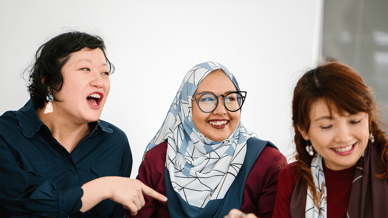 Three women of older adult age photographed smiling together in a social or wellness setting. The group dynamic conveys connection and peer support, representing the mental health, work, and relationships section.