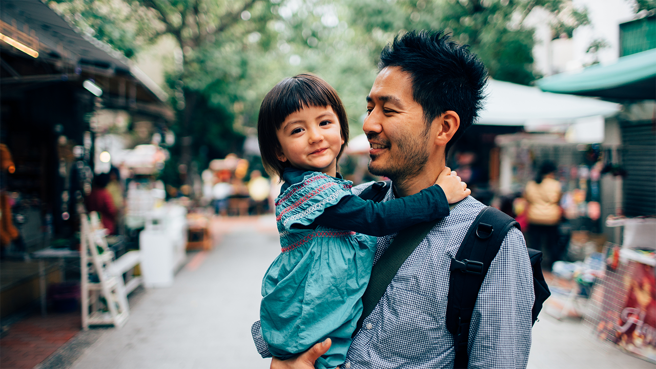 An adult and a young child share a relaxed, affectionate moment in an everyday environment, evoking the family relationships, personal goals, and life priorities that are inseparable from any patient's treatment journey.