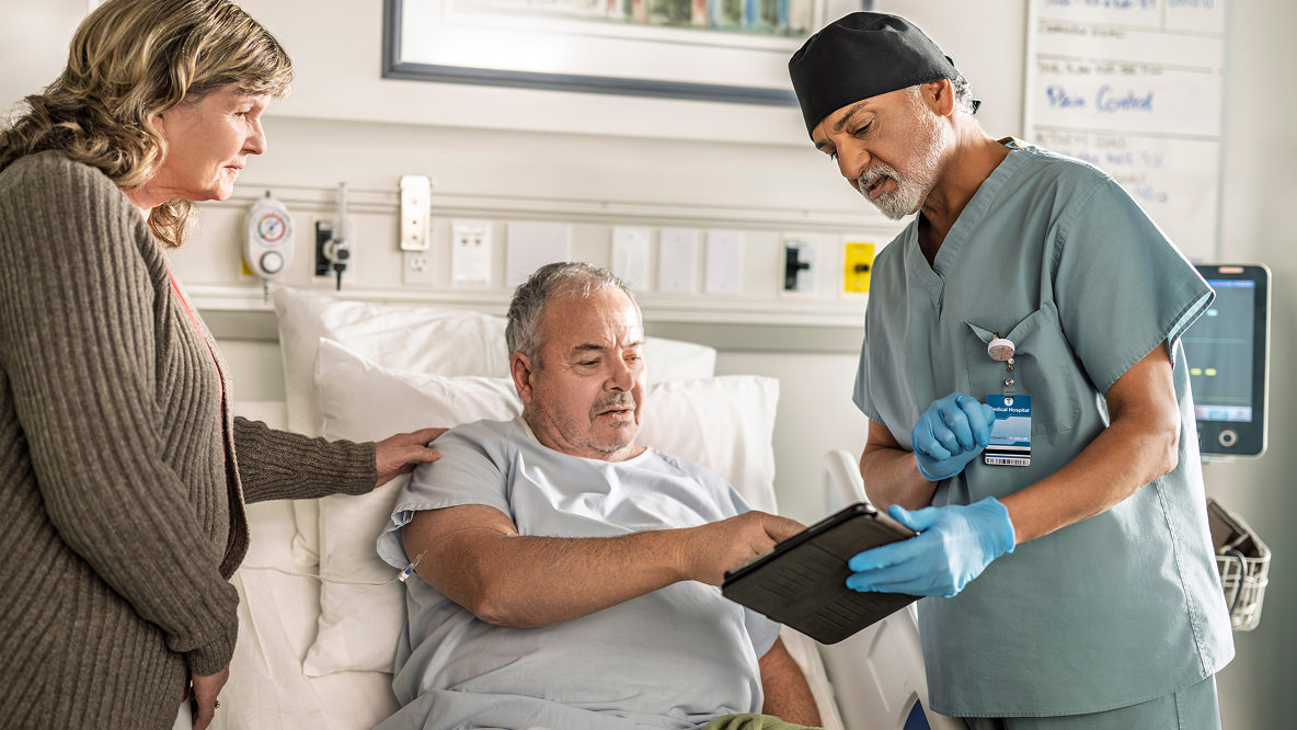 Older patient with a healthcare professional in a warm clinical  setting. Their proximity and engaged posture conveys partnership and mutual support, representing the treatment goals section of this FAQ page.